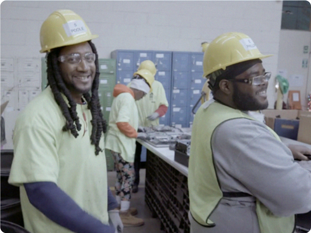 Two men with hard hats on smiling at the camera.